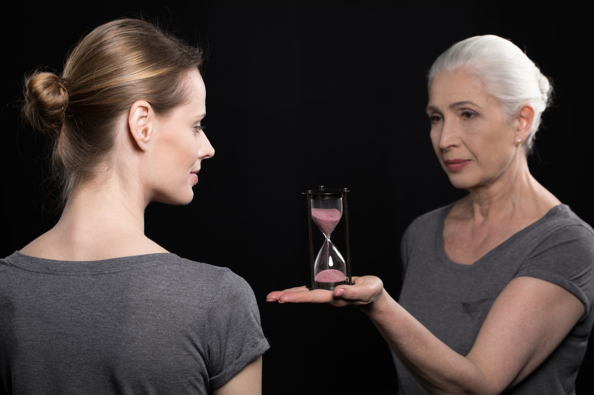 Older woman showing hour glass to her daughter